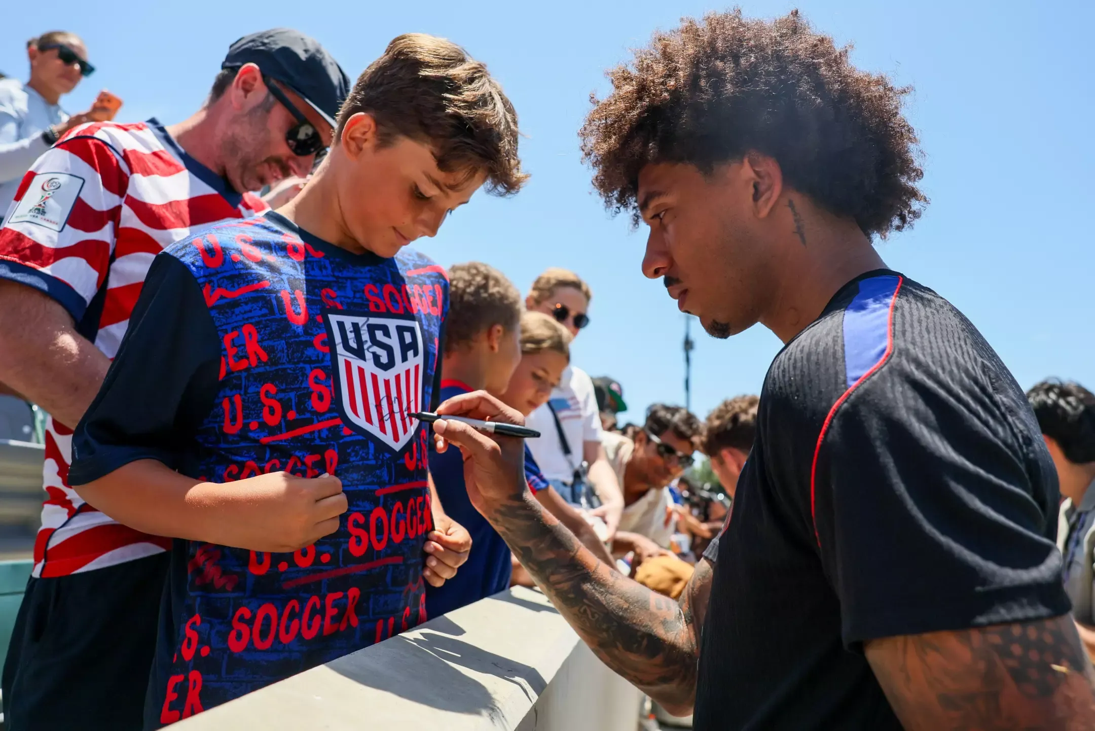 Irvine, CA - June 08: USMNT player Chris Richards autographs the shirt of a young fan.