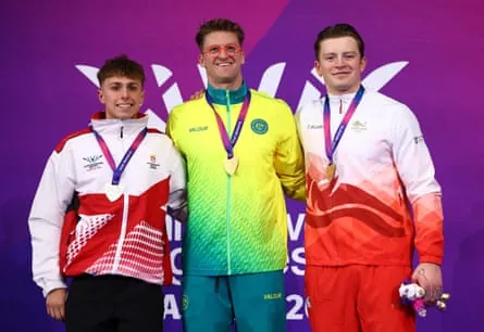 Sam Williamson celebrates on the podium after winning the men’s 100m breaststroke final with Jersey’s Filip Nowicki and England’s Adam Ramsay-Peaty.