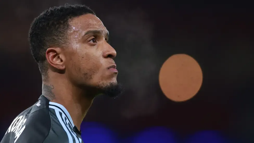 Ezri Konsa looks on wearing a black Aston Villa kit
